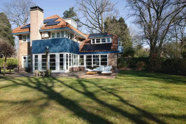 Achterzijde villa met uitbouw en openslaande deuren naar tuin – Het Gooi